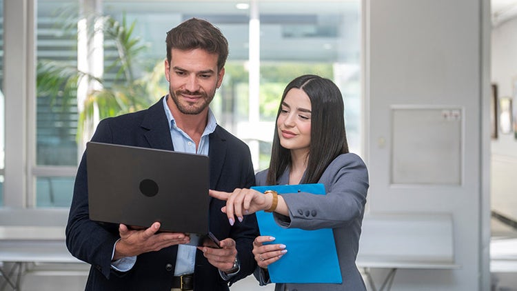 Des collègues en pleine collaboration devant un ordinateur portable dans un environnement de bureau