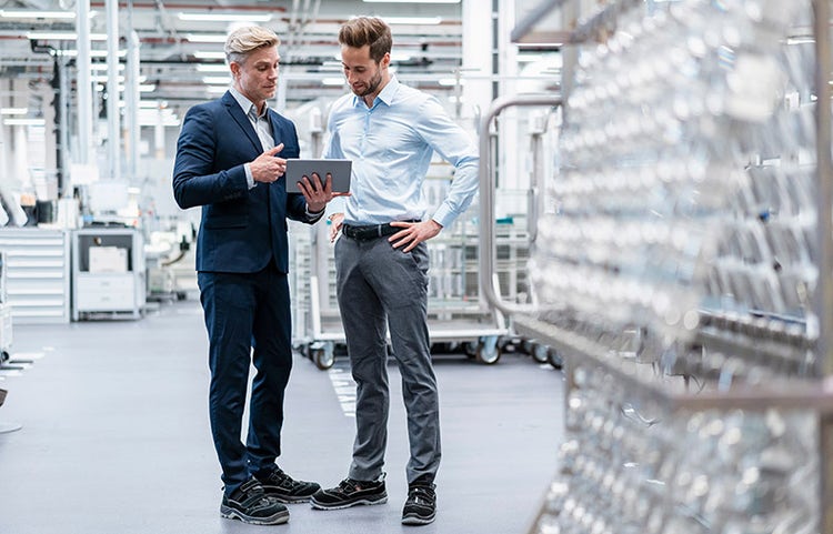 Deux professionnels examinent des données sur une tablette dans un environnement d'usine moderne