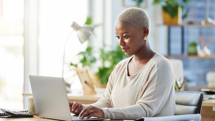 Vrouw glimlacht en typt op een laptop