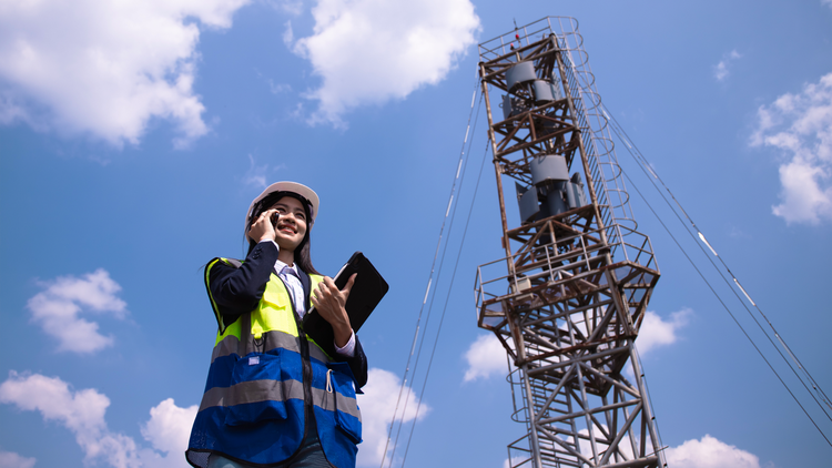 AI in telecom: vrouwelijke telecommedewerker aan de telefoon in de buurt van een zendmast