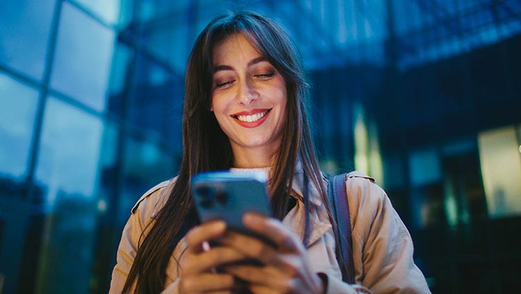 Glimlachende vrouw die naar haar telefoon kijkt