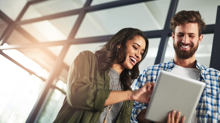 Twee lachende mensen achter een tablet