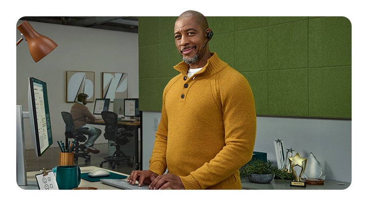 Een nieuwe kijk op CRM: een man met een headset lacht naar de camera terwijl hij typt op een toetsenbord