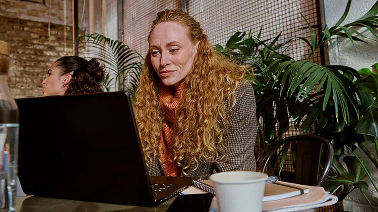 Operating excellence: A woman sits at a table working on a laptop.