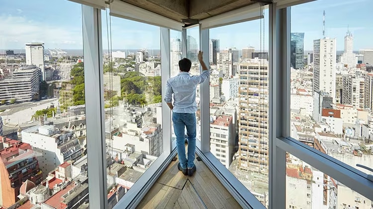 Innovation is a top management imperative: man standing in a corner office overlooking a city