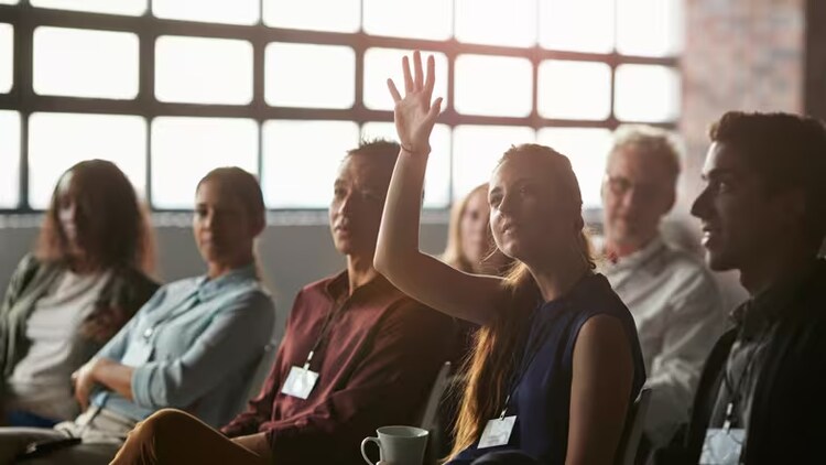 Skills of the future: young woman raises hand in training session