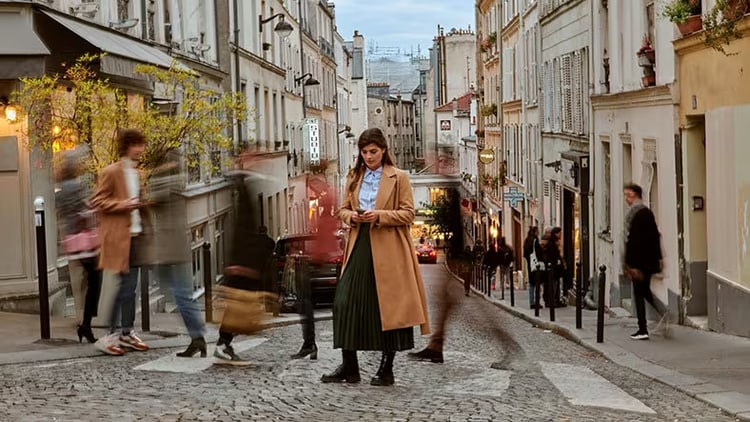 Experience Can Drive Better Brand Loyalty: Lady standing outside looking at her phone with people walking around her