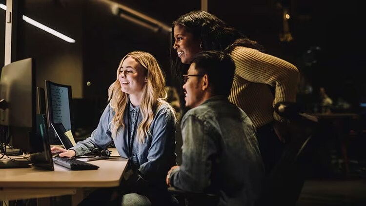 GenAI in customer experience: three workers smiling at a computer monitor