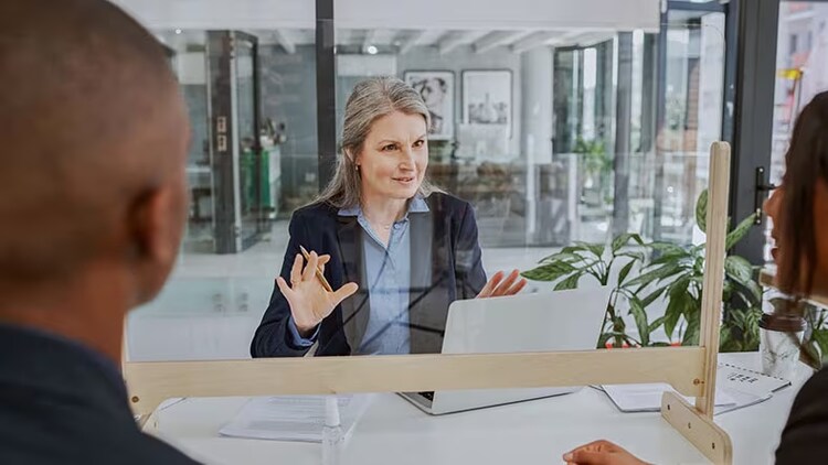 Sustainability in banks: woman financial worker with a plant on her left in conversation with a couple of people