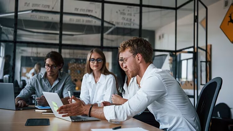 GenAI adoption: Group of workers looking at laptops in a conference room