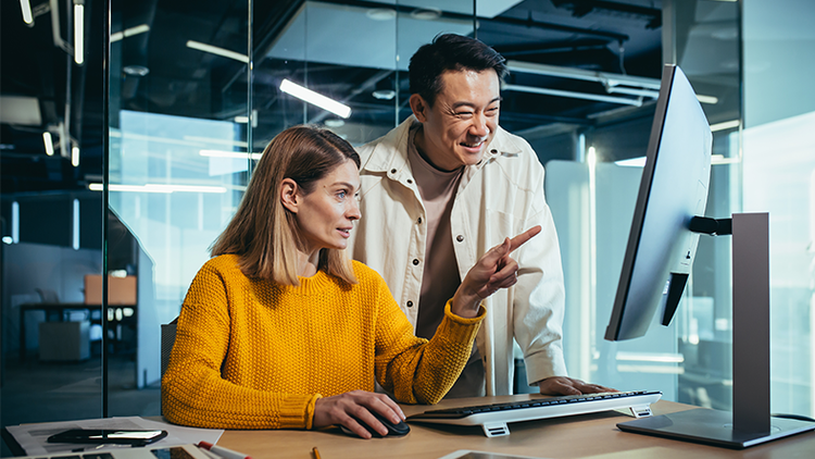 InfoSec: two employees looking at a computer monitor in an office