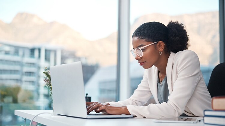 Power of low code: woman typing on a laptop in a high-rise office