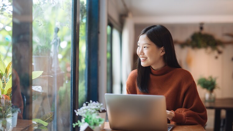 Industry momentum: woman at an open laptop smiling at an adjacent window