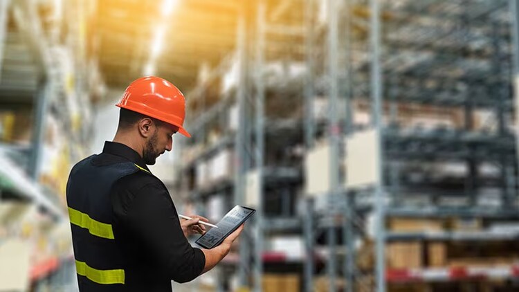 Supply Chains: male worker using tablet device in warehouse environment.