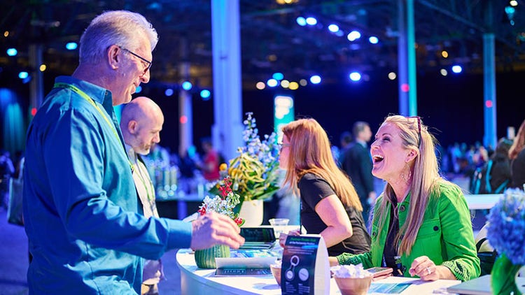 Two people talking and smiling at a conference stand.
