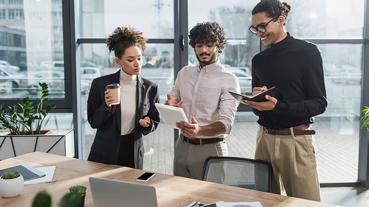 Three office workers looking at a tablet device