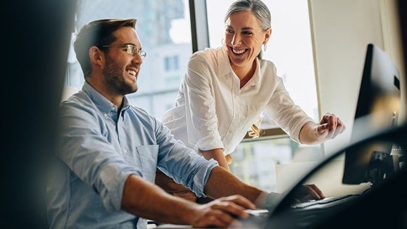 Smiling coworkers looking at a computer screen