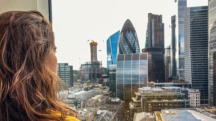 UK business investment: woman looking through a window at London's skyline