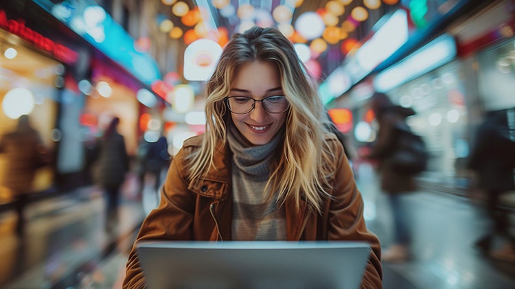 Smiling woman in the city working on laptop