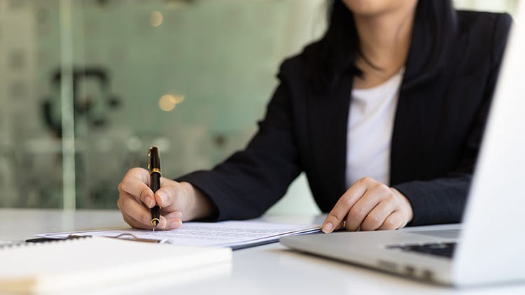 Business woman holding a pen signing a document