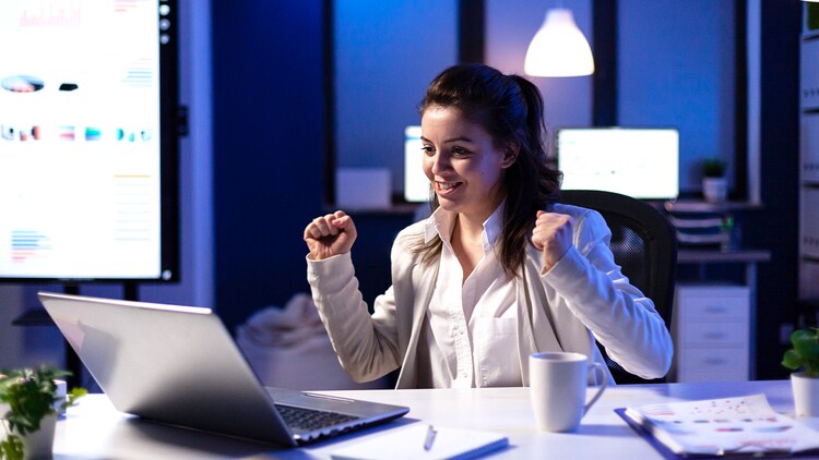Levels of AI: woman at a desk doing fist pumps at an open laptop