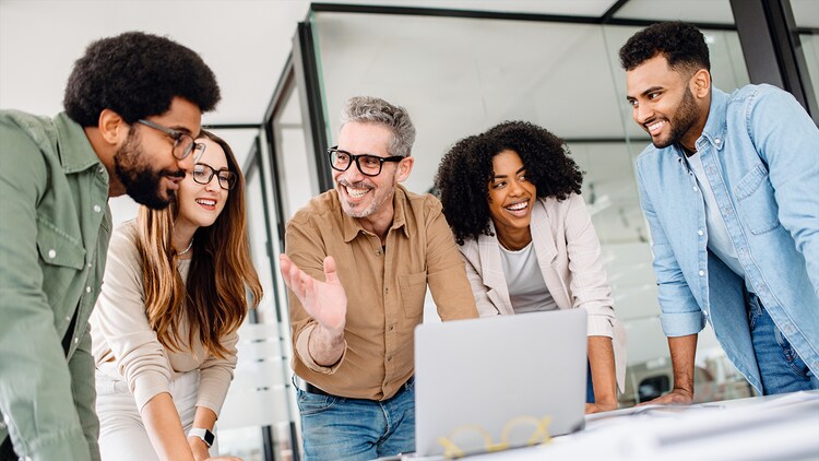 ServiceNow partner experience: Five office workers gathered around an open laptop, smiling at each other