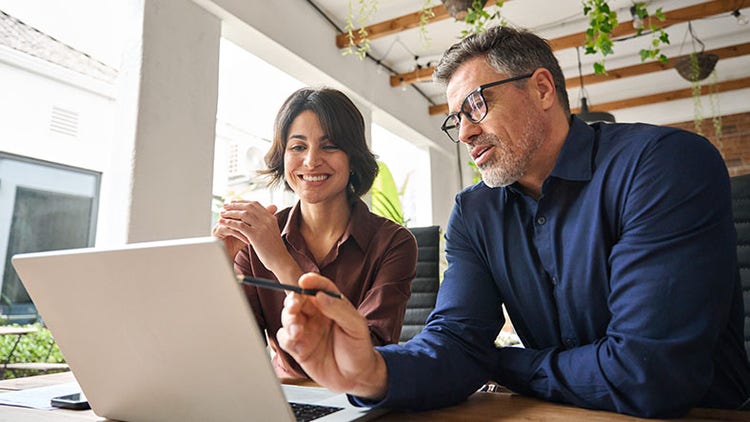 Two people collaborating at a desk in an office setting
