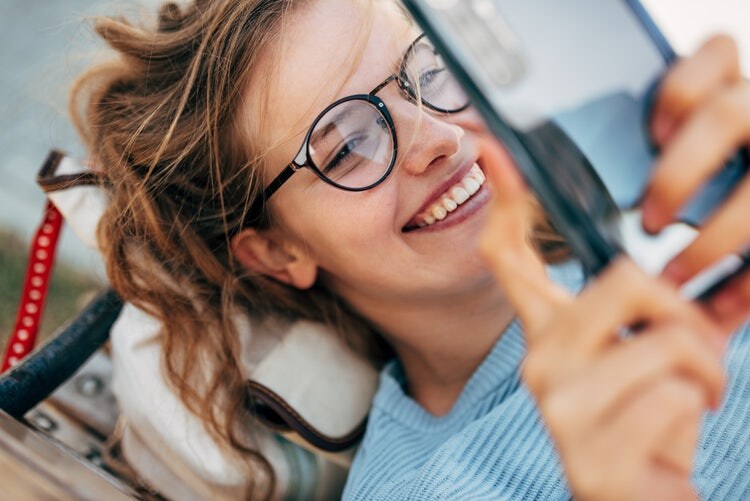Close up of a happy woman lying down whilst using mobile phone