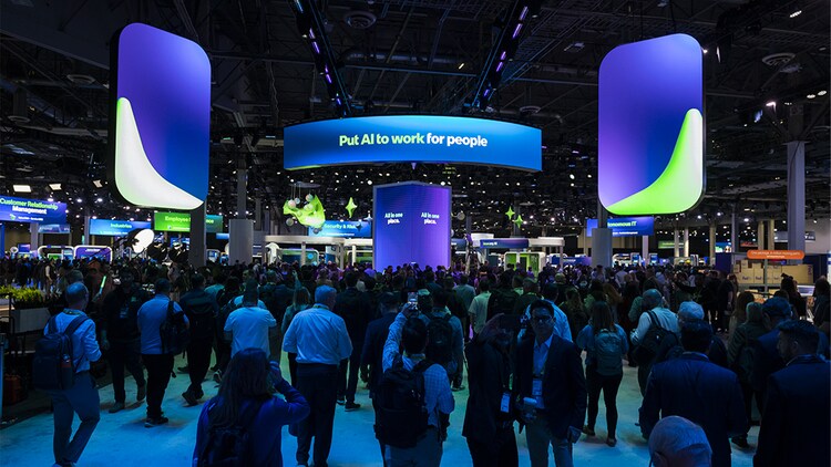 A crowd of people on the Knowledge expo floor under a banner that reads “Put AI to work for people”