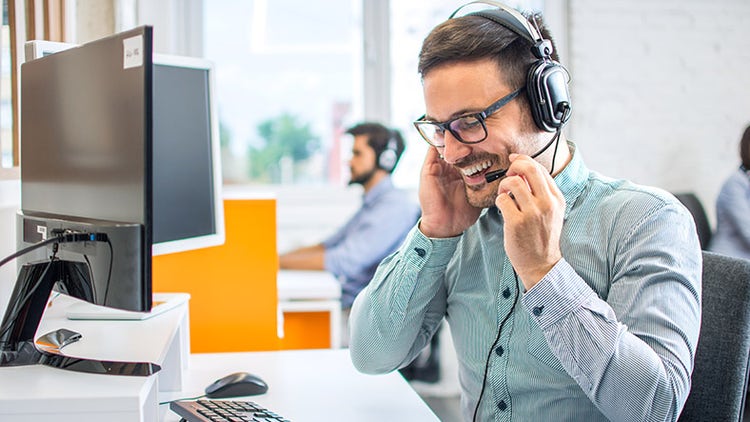 Customer service executive smiling whilst taking a customer call.