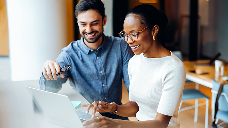 Two employees sitting together looking at a shared laptop
